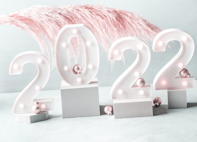 New year 2022 lights numbers with pink pampas branch and golden decor on gray geometric podiums. Minimal celebrating new year scene